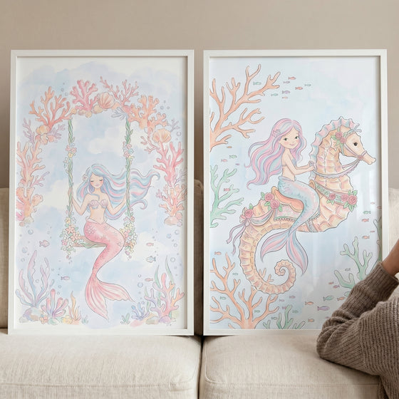 Two pastel illustrations of a mermaid on a swing and one on a seahorse as soft mermaid wall art set of 2.