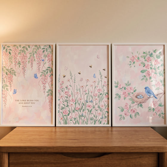 Soft pink whimsical garden wall art set of 3 with wisteria, wildflowers, and a bluebird nest on a wooden dresser.