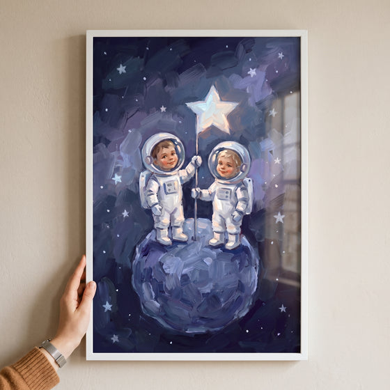 A hand holds a framed star flag toddler astronauts wall art of two children in space suits on a blue moon.