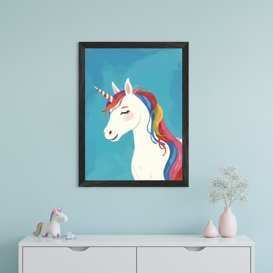 Modern nursery with a white dresser against a light blue wall. A black-framed whimsical illustration of a white unicorn with a rainbow mane and striped horn, on a blue background, hangs centered above the dresser. A unicorn figurine and pink vases with flowers are on the dresser.