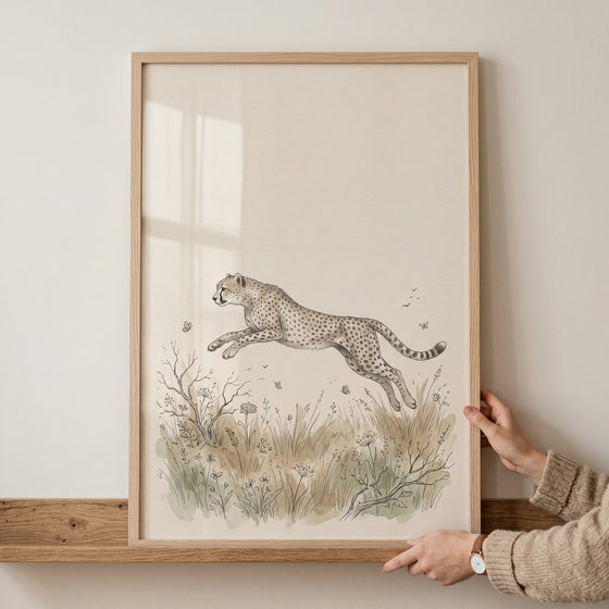 Vintage earth tone cheetah artwork featuring a leaping cheetah over a grassy field, held in a light wood frame.
