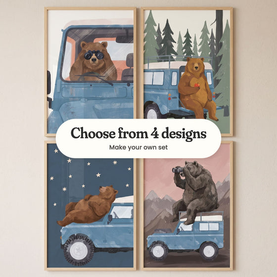 Four bear and blue truck prints in light wood frames in two rows on a cream wall: a bear at the wheel looking through binoculars, a bear holding an apple on the back step, a bear lying on the hood under the stars and a bear on the roof with binoculars, with a label reading Choose from 4 designs, Make your own set