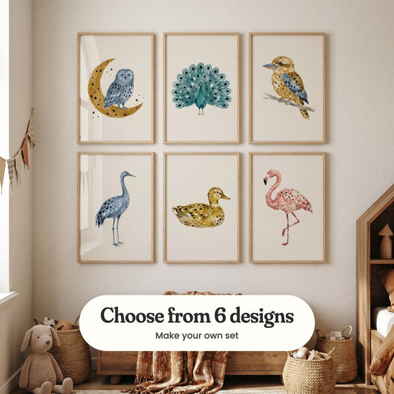 Kids' room with six spotted bird prints in light wood frames in two rows above a wooden toy chest with a rust patterned throw, beside woven baskets, a plush bunny, a fabric bunting and a little house bed: Midnight Moon Owl, Azure Plume Display, Golden Kookaburra Art, Blue Spotted Crane, Golden Spotted Duck and Spotted Pink Flamingo, with a label reading Choose from 6 designs, Make your own set