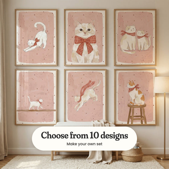 Nursery with six cat prints in light wood frames in two rows above a light wood changing table with a linen throw, beside a basket of plush teddies and a floor lamp: Starry Kitten Stretch, Fancy Gingham Cat, Starry Feline Friends, Starry Cat Walk, Starry Scarf Cat and Starlit Ginger Cat, with a label reading Choose from 10 designs, Make your own set