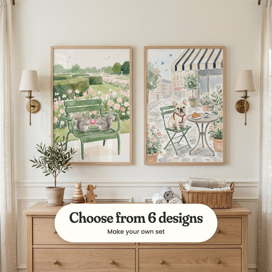 Cream panelled nursery with two Paris prints in light wood frames between two brass wall lamps, above a light wood dresser with a small olive tree, wooden toys and a basket of rolled towels, between linen curtains: Squirrel Garden Picnic and Parisian Cafe Dog, with a label reading Choose from 6 designs, Make your own set