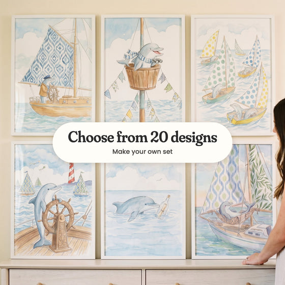 Six dolphin sailor prints in white frames standing on a cream dresser, with a woman beside them: a dolphin captain at the wheel, a dolphin in a crow's nest, dolphins in polka-dot sailboats, a dolphin at a carved wheel with a lighthouse, a dolphin with a message in a bottle and a dolphin napping in a hammock, with a label reading Choose from 20 designs, Make your own set