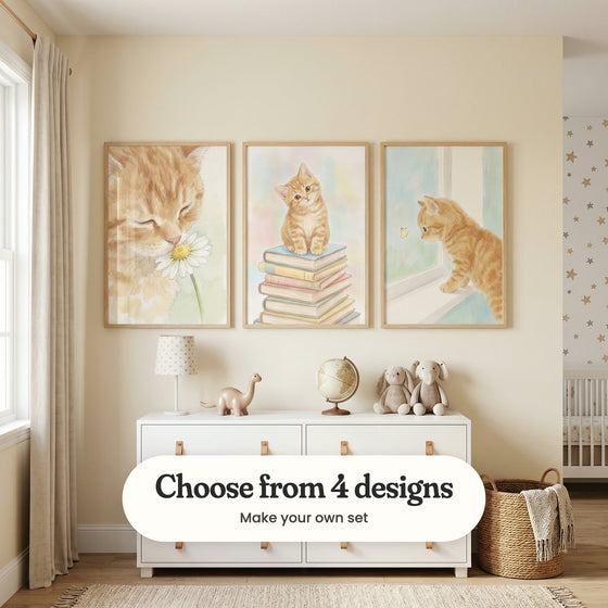 Cream nursery with three ginger kitten prints in light wood frames above a white dresser with a lamp, a globe, a toy dinosaur and plush toys, beside a woven basket: Sweet Floral Whiskers, The Bookish Tabby and Curious Ginger Kitten, with a label reading Choose from 4 designs, Make your own set