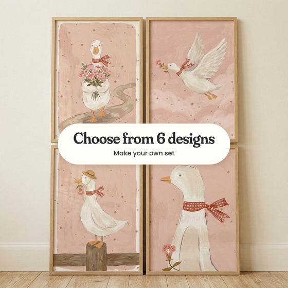 Four goose prints in light wood frames leaning against a cream wall on a wood floor: a goose carrying a bouquet down a winding path, a goose flying through pink clouds, a goose in a straw hat on a fence post and a close-up goose with a red gingham bow, with a label reading Choose from 6 designs, Make your own set