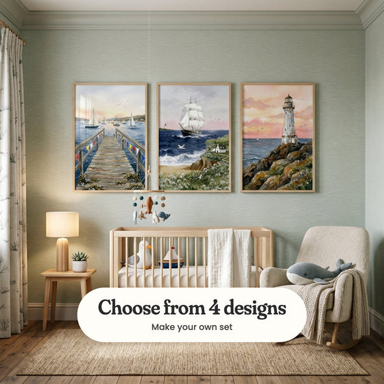 Sage green nursery with three seaside prints in light wood frames above a light wood crib with a plush seagull and a toy sailboat, beside a felt sea animal mobile, an armchair with a plush whale and a side table with a lamp: Harbor Pier View, Ocean Breeze Journey and Sunset Coastal Beacon, with a label reading Choose from 4 designs, Make your own set