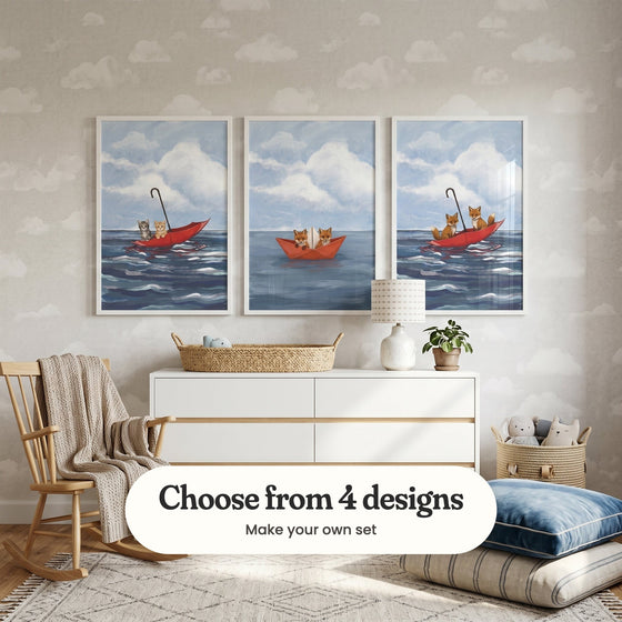 Nursery with cloud wallpaper and three floating animal prints in white frames above a white dresser with a woven basket, a lamp and a plant, beside a rocking chair, a basket of plush toys and floor cushions: Floating Feline Friends, Paper Boat Voyage and Foxes Adrift, with a label reading Choose from 4 designs, Make your own set