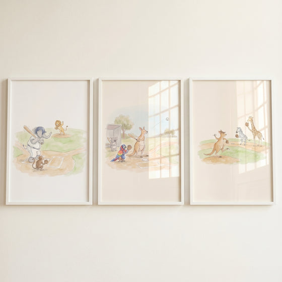 Watercolor baseball playing animals wall art set of 3 features an elephant, kangaroo, and giraffe in white frames.