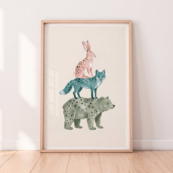 Spotted pink rabbit, blue fox, and green bear stacked in watercolor bear fox rabbit wall art in a light wood frame.