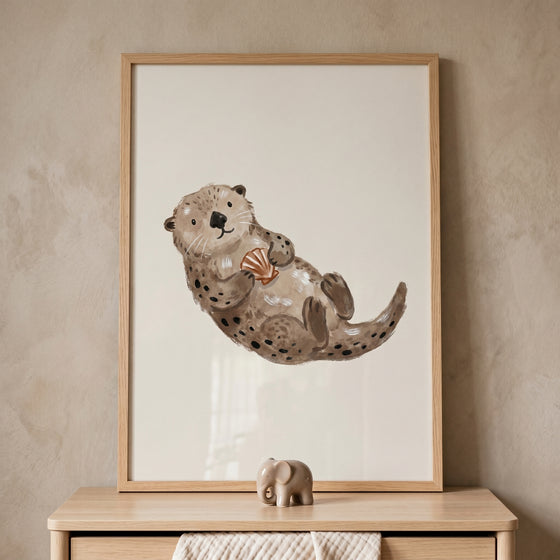 Framed watercolor brown sea otter wall art of a sea otter holding a shell above a wooden dresser.