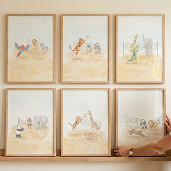 Watercolor volleyball safari animals wall art set of 6 with tigers, giraffes, and elephants playing on a sandy court.