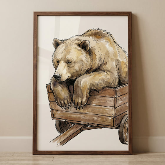 Framed watercolor wooden cart bear wall art shows a brown bear leaning over the side of a rustic wooden wagon.
