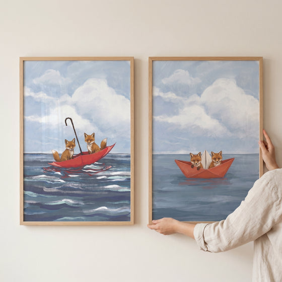 Two foxes in an umbrella and two in a paper boat in this whimsical blue ocean foxes wall art set of 2.