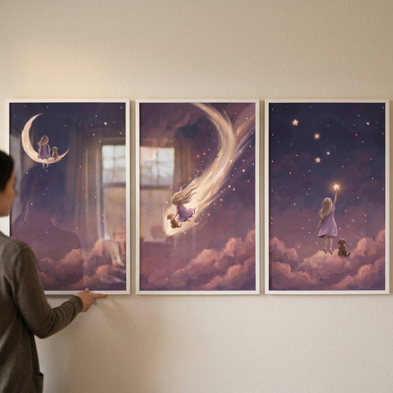 Woman hangs a whimsical indigo girl dog wall art set of 3 featuring a child and pet among the moon, stars, and clouds.