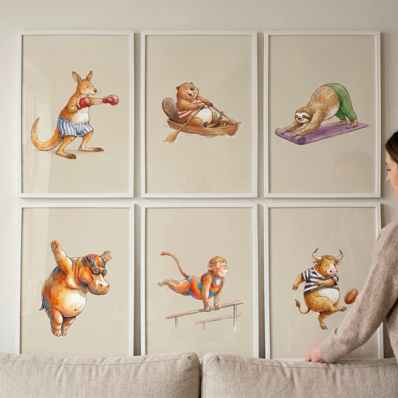 Whimsical watercolor sports animals wall art set of 6 with a boxing kangaroo, rowing beaver, sloth, hippo, monkey, and bull.