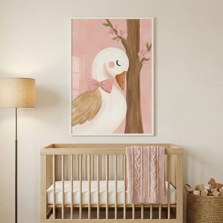 An interior scene of a minimalist nursery features a light-toned wooden crib placed against a plain, neutral wall. Centered above the crib is a large framed piece of art showing a stylized white goose with its eyes closed, wearing a pink polka-dot bow tie. The goose has tan-colored wings and stands next to a slender brown tree trunk adorned with small pink flowers. The background of the illustration is a soft, solid pink.