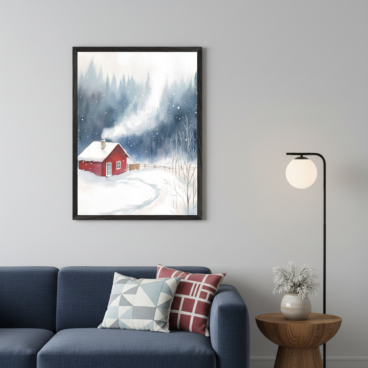 Living room with a blue sofa and two patterned pillows. Above the sofa, a framed watercolor painting shows a red cabin in a snowy forest with chimney smoke. A black floor lamp stands right of the sofa. A wooden side table with a white vase is next to the lamp.