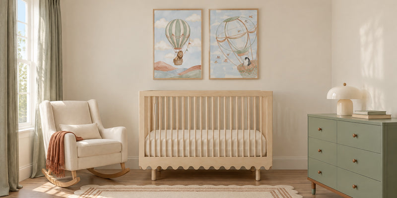 Adventure nursery: hot air balloon prints of a lion and a penguin above a birch crib, with a cream rocker and a sage dresser