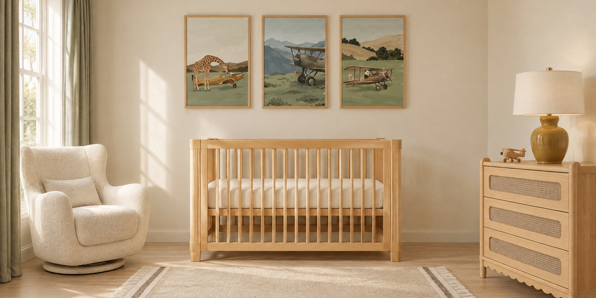 Airplane nursery: three sage green animal pilot prints above a natural wood crib, with an ivory glider, cane dresser and sand wool rug