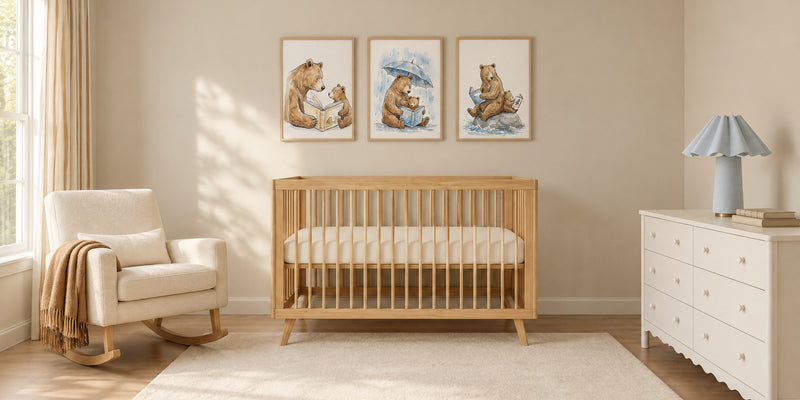 Bear nursery: a honey pine crib under three framed watercolor-style prints of bears reading with their cubs, an ivory rocker and a white dresser with a blue lamp