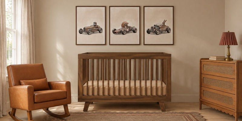 Car nursery: three vintage racing car prints of a badger, a squirrel and a rabbit above a walnut crib, with a cognac leather rocker and a cane dresser