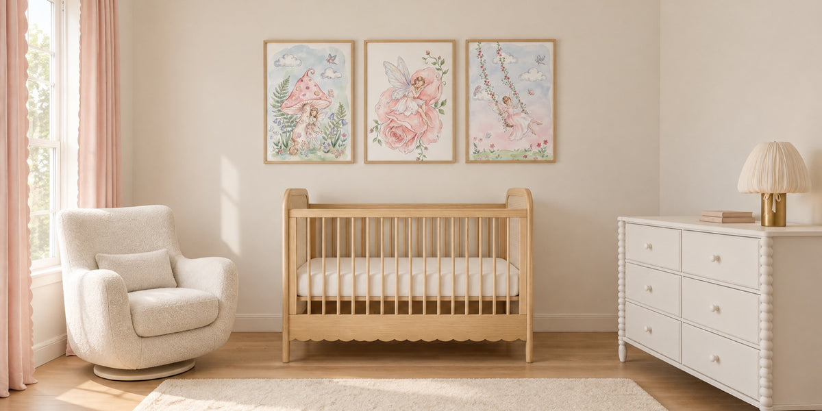 Fairy nursery: three soft watercolor-style fairy prints above a light oak crib, with blush curtains and an ivory glider
