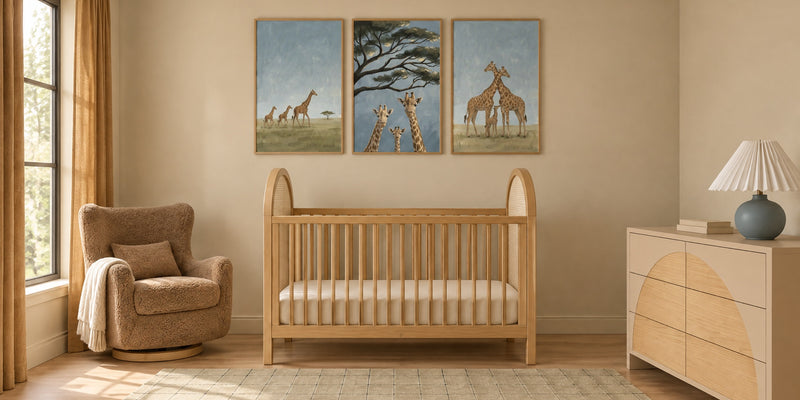 Giraffe nursery: a honey wood cane crib under three dusty blue giraffe family prints, with a caramel shearling glider and a sand dresser