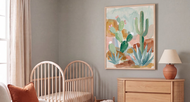 Gender-neutral nursery in dusty sage with a natural-wood crib, cream boucle glider, oak dresser, terracotta lamp, and Canyon Bloom desert art above the dresser