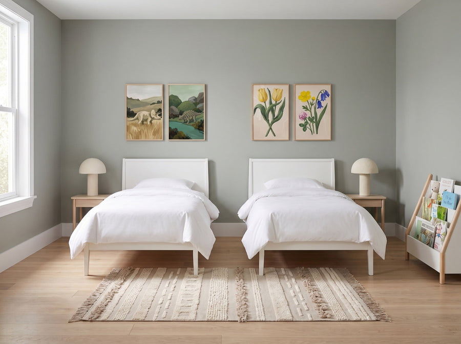 Boy and girl shared kids room in sage green with two twin beds, dinosaur and wildflower wall art