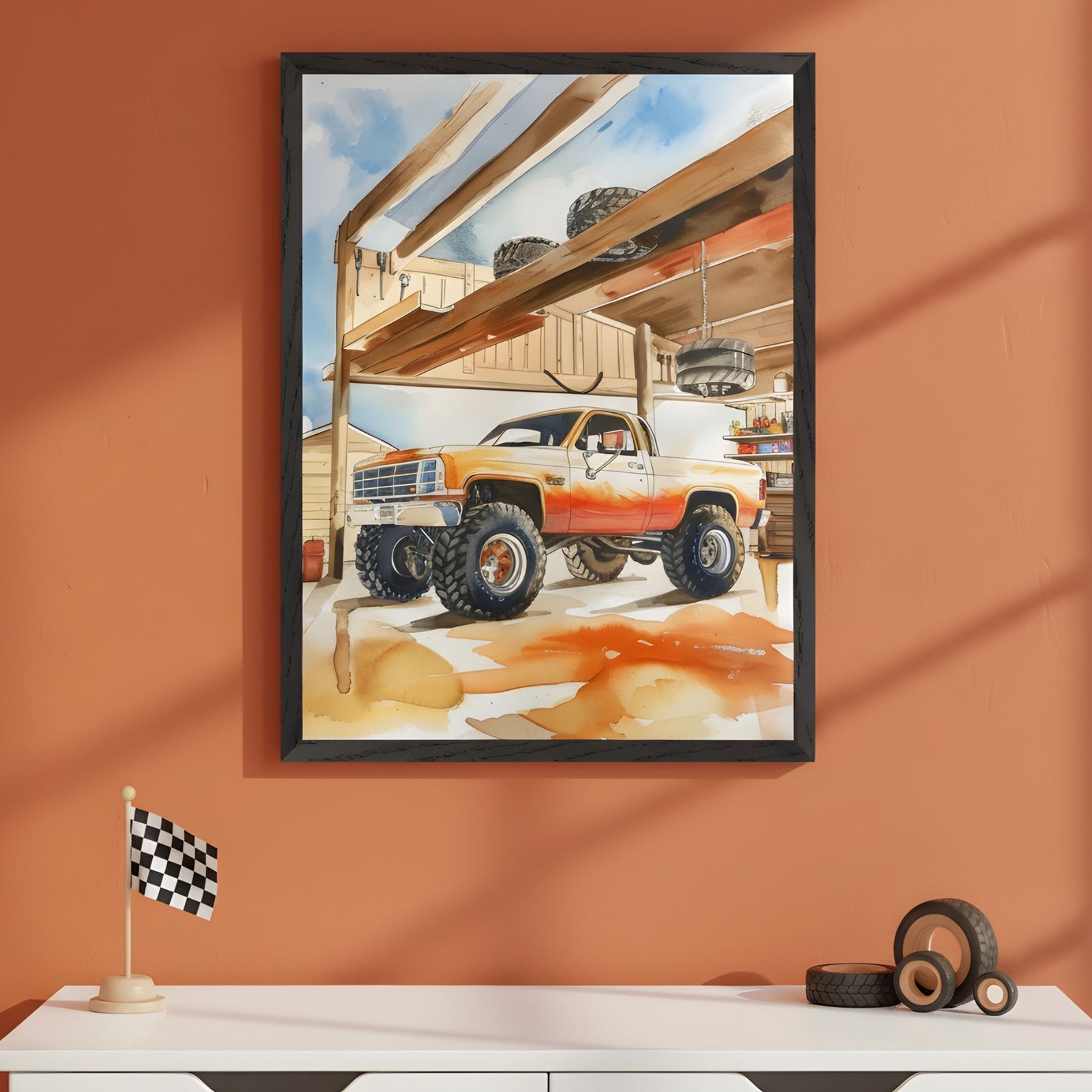 Framed illustration of a lifted orange and white pickup truck parked inside a sunlit garage with exposed wooden beams and scattered tools. The scene captures a mix of rugged utility and warmth, with oversized tires, a checkered floor mat, and soft watercolor textures adding charm and motion.