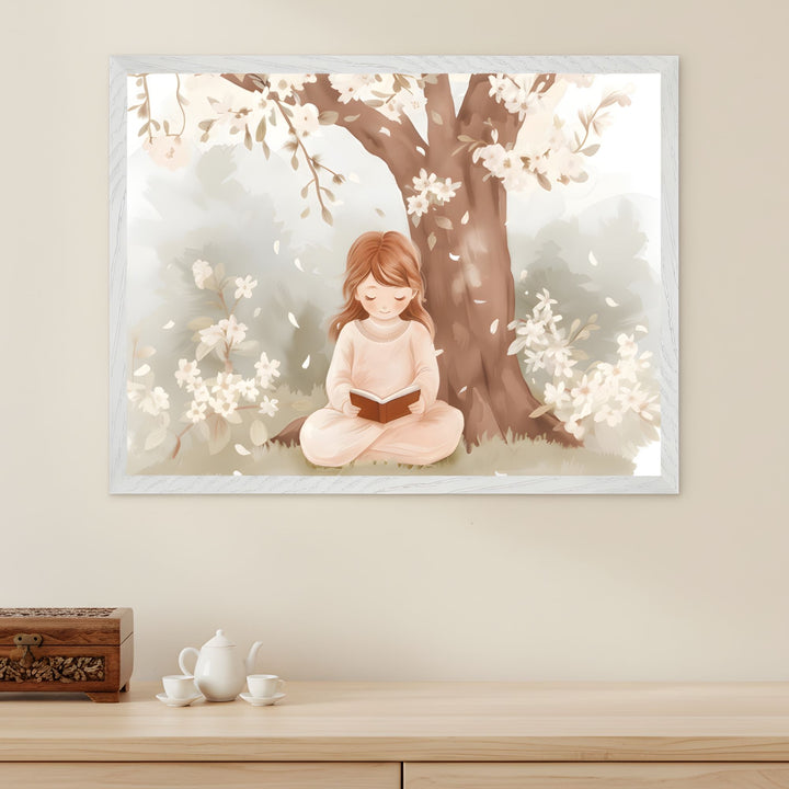 Framed wall art of a young girl sitting cross-legged under a blooming tree, peacefully reading a book amid soft white flowers and falling petals. The gentle pastel tones and serene setting create a calming, storybook-inspired atmosphere in the room.