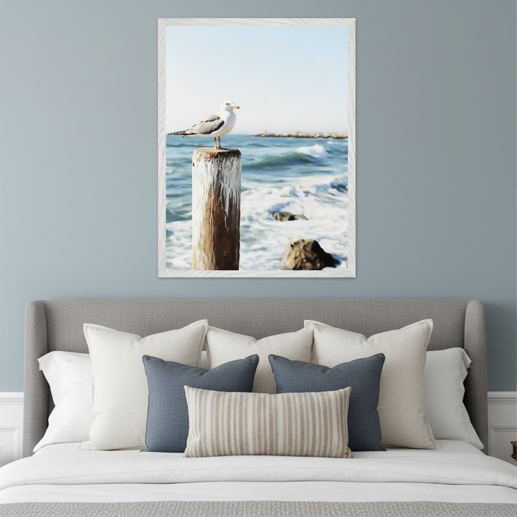 Bedroom with a gray upholstered bed and headboard. A large framed painting of a seagull on a wooden post in the ocean, rendered in a painterly style, hangs centered above the bed.