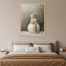 Modern bedroom with a bed and gray headboard. A large framed painting in a rustic painterly style hangs centered above the bed, depicting a snowman wearing a brown top hat and scarf in a snowy setting.
