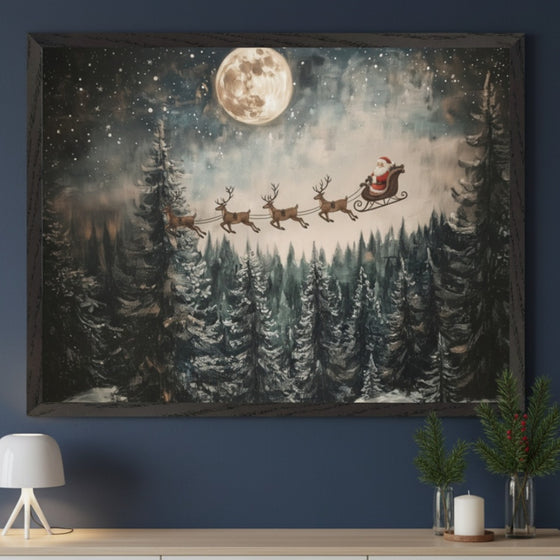 Modern living room featuring a light-colored console table. A large framed Christmas painting of Santa and reindeer flying over a snowy forest under a full moon hangs centered above the table. A white lamp, pine branches, and a candle adorn the console.
