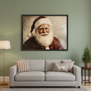 Living room with a gray sofa. A large framed portrait of Santa Claus with a red hat and white beard, featuring a snowy backdrop, hangs above the sofa. A gold floor lamp is on the left; a small lit Christmas tree sits on a side table to the right.