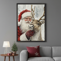 Modern living room with a gray sofa. A large framed painting of Santa Claus hugging a reindeer with a snowy background hangs above the sofa. A wooden side table with a lamp and small Christmas tree is to the left.