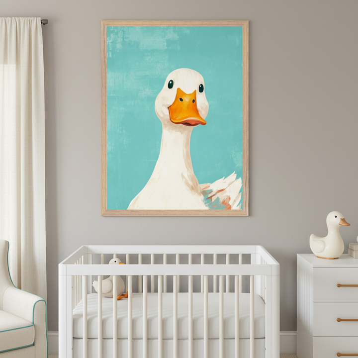 Modern nursery with a white crib. Above it hangs a large framed art print of a white duck with an orange beak against a teal background. A white dresser is on the right, and an armchair with blue trim is on the left.