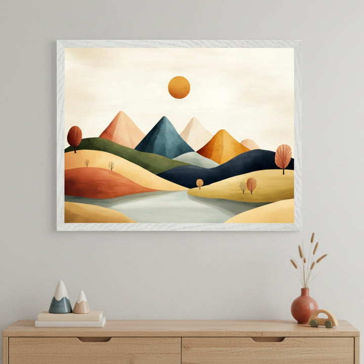 Modern kid's room with a light wood dresser. A large white-framed minimalist landscape print hangs above the dresser, depicting layered colorful mountains, a winding river, an orange sun, and stylized trees.