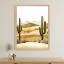 Modern room with a light wood dresser. Above it, a framed stylized desert landscape print depicts saguaro cacti, dunes, and mountains. A vase with a palm leaf and a small cactus figurine are on the dresser.