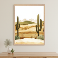 Modern room with a light wood dresser. Above it, a framed stylized desert landscape print depicts saguaro cacti, dunes, and mountains. A vase with a palm leaf and a small cactus figurine are on the dresser.