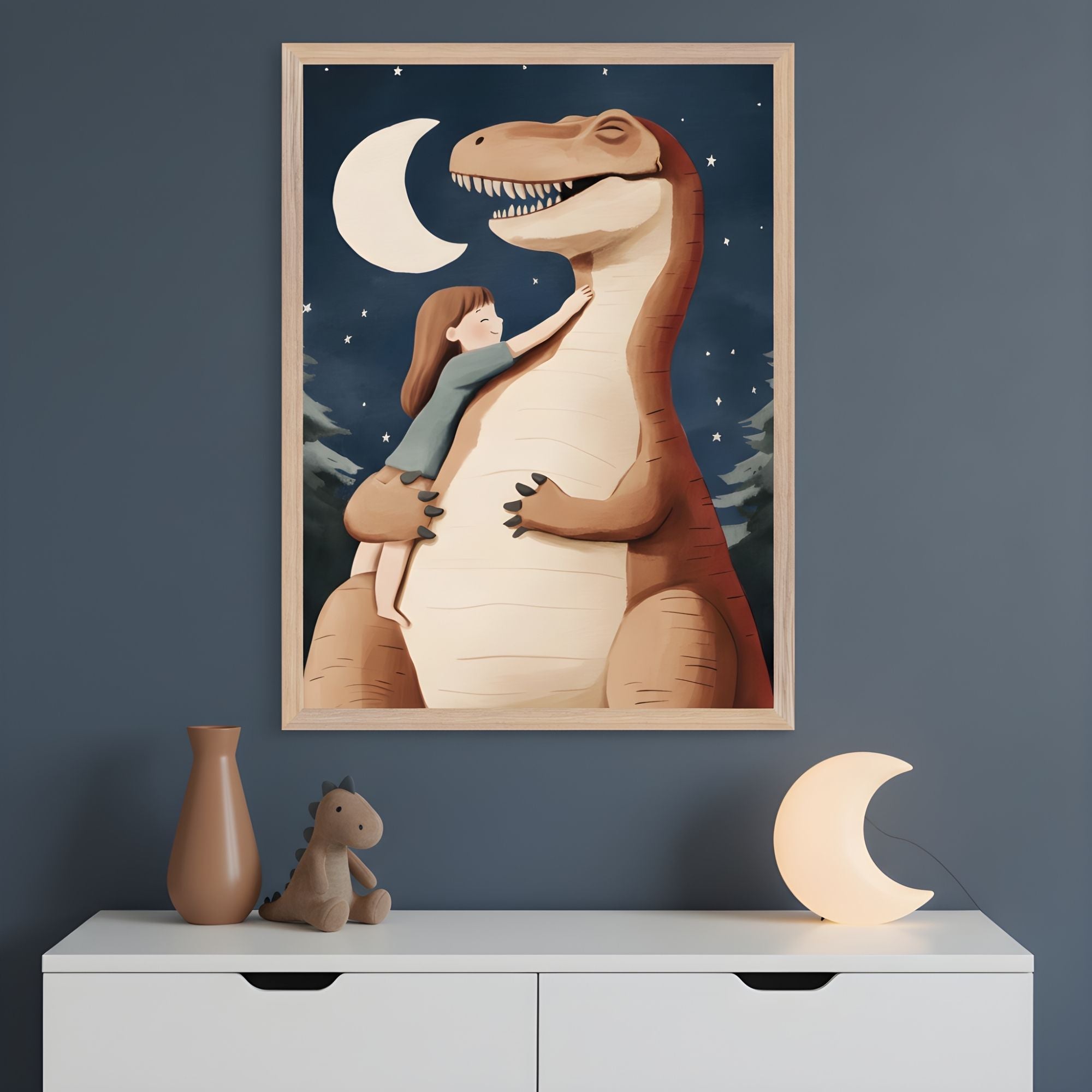 A framed illustration depicts a young girl hugging a friendly T. rex under a crescent moon and starry night sky, with pine trees silhouetted in the background. The artwork hangs above a white dresser decorated with a moon-shaped night light, a brown vase, and a plush dinosaur toy.