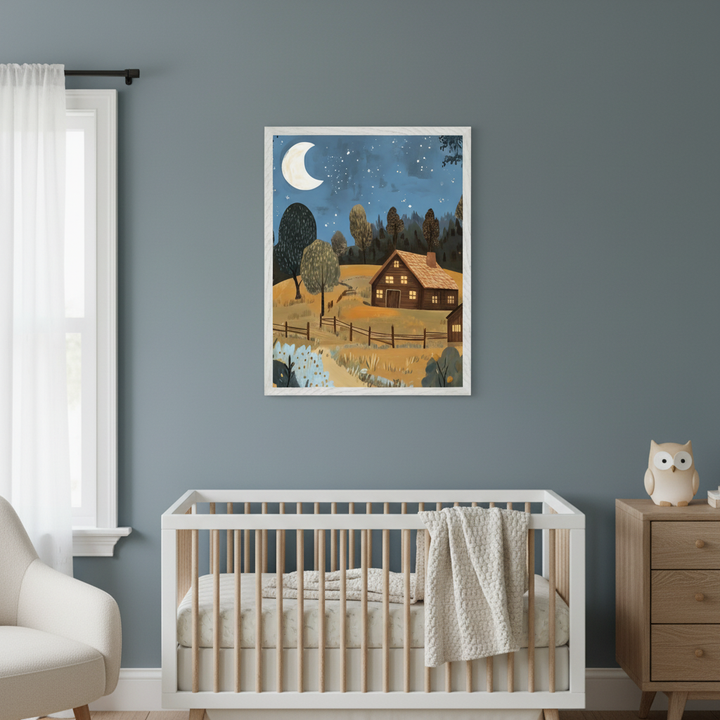 Modern nursery with a white crib. A framed illustrative print of a night landscape with a lit wooden cabin, crescent moon, and stars hangs centered above the crib. A wooden dresser is on the right.