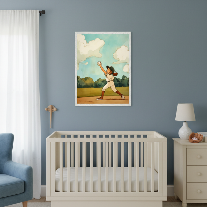 Modern nursery with a white crib, blue armchair, and white dresser against a blue wall. A framed cartoon illustration of a girl pitching a baseball on a field hangs above the crib.