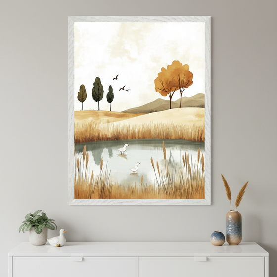 Framed wall art depicting a calm autumn landscape with a small pond surrounded by tall golden grasses, two white birds wading in the water, and distant hills with stylized trees. The artwork hangs above a white cabinet adorned with vases, dried grasses, and a ceramic bird, creating a serene and nature-inspired decor.