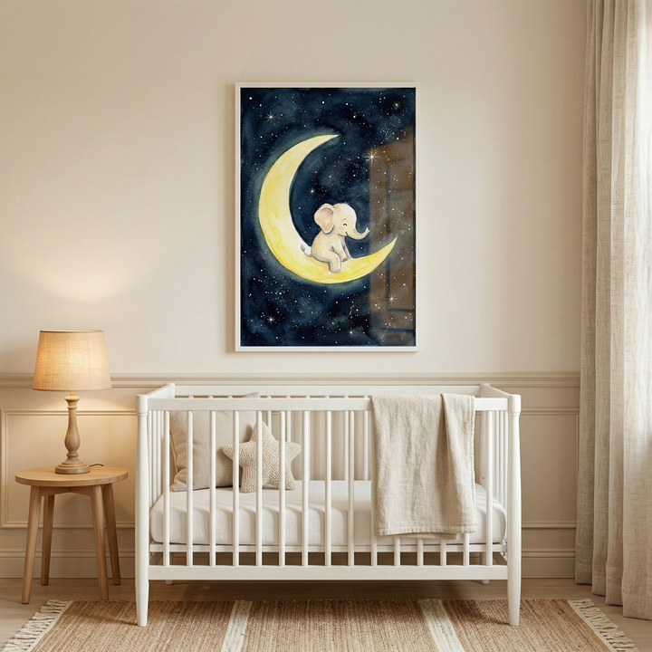 A cozy, neutral-toned nursery features a white wooden crib centered against a light-colored wall. Above the crib hangs a framed vertical illustration depicting a small, light-gray cartoon elephant sitting peacefully on a bright yellow crescent moon. The background of the artwork is a deep blue night sky dotted with many small, glowing stars. 
Inside the crib, there is a soft-textured pillow, a star-shaped plush cushion, and a tan blanket draped over the rail. 