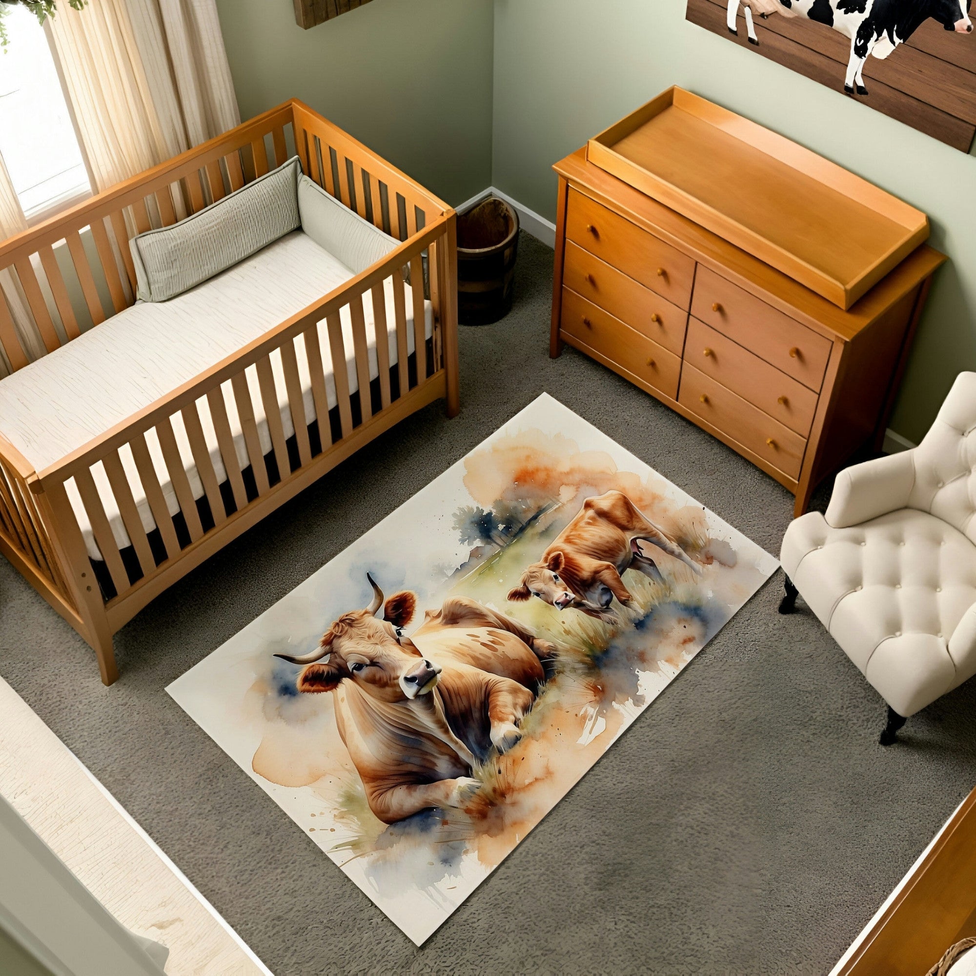 The nursery rug displays a watercolor illustration of a serene cow reclining in a grassy meadow alongside a playful calf. The artwork is surrounded by soft hues of green and orange, giving a warm and pastoral ambiance. Ideal for a farm-themed or countryside-inspired nursery setting.