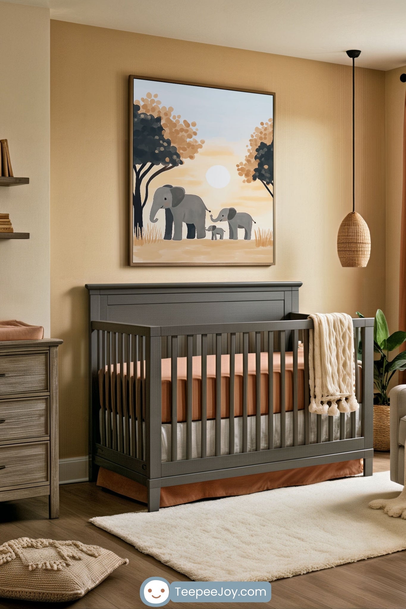 Serene nursery decorated in earthy tones, featuring a dark gray crib with terracotta bedding and a cream knit blanket draped over the side. Above the crib hangs a framed artwork of three elephants of two adults and a baby walking together under a soft sun with stylized trees in the background. The room includes a wooden dresser, cozy rug, woven pendant light, and natural decor touches for a calming, safari-inspired vibe.